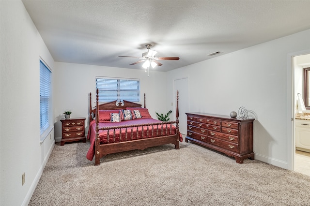 carpeted bedroom with ceiling fan, a textured ceiling, and ensuite bath