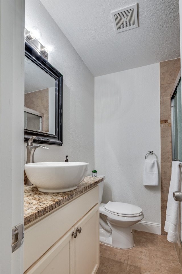 bathroom with vanity, tile patterned floors, toilet, a textured ceiling, and a shower with shower door