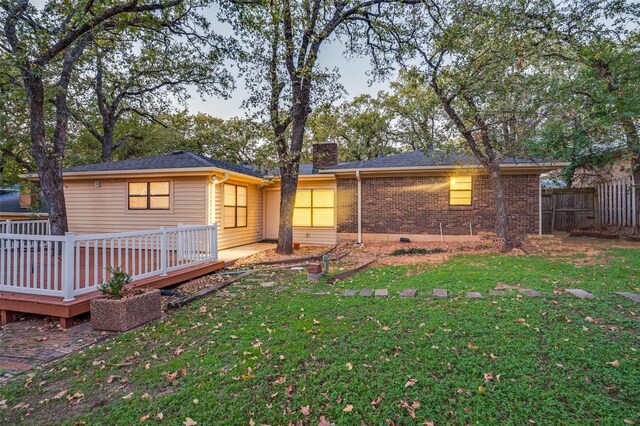 rear view of house featuring a wooden deck and a yard