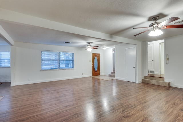 unfurnished living room featuring ceiling fan, hardwood / wood-style floors, and a textured ceiling