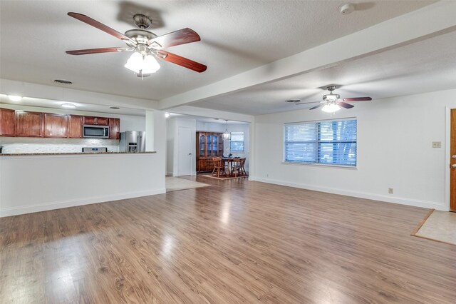 unfurnished living room with ceiling fan, light hardwood / wood-style floors, and a textured ceiling