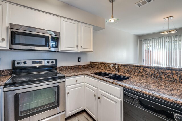 kitchen featuring white cabinets, hanging light fixtures, sink, and appliances with stainless steel finishes