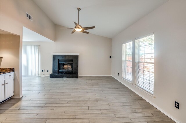 unfurnished living room with ceiling fan, a premium fireplace, lofted ceiling, and light wood-type flooring