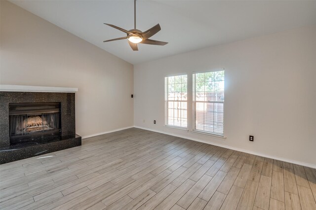 unfurnished living room featuring a premium fireplace, ceiling fan, vaulted ceiling, and light wood-type flooring