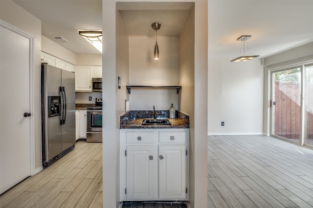 kitchen with decorative light fixtures, sink, white cabinetry, and stainless steel appliances