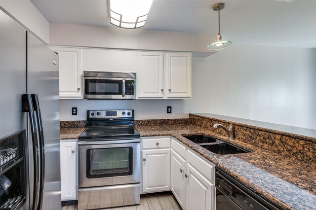 kitchen featuring white cabinetry, sink, pendant lighting, appliances with stainless steel finishes, and light wood-type flooring