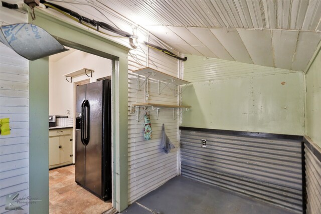 interior space with black refrigerator with ice dispenser
