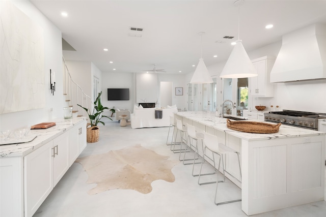 kitchen featuring a large island, sink, white cabinetry, and premium range hood