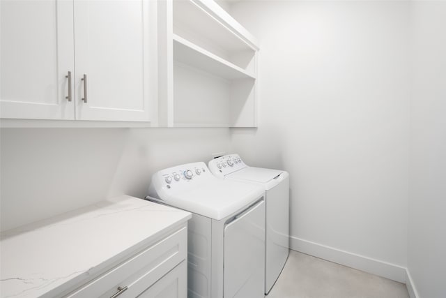 clothes washing area featuring cabinets and washing machine and dryer