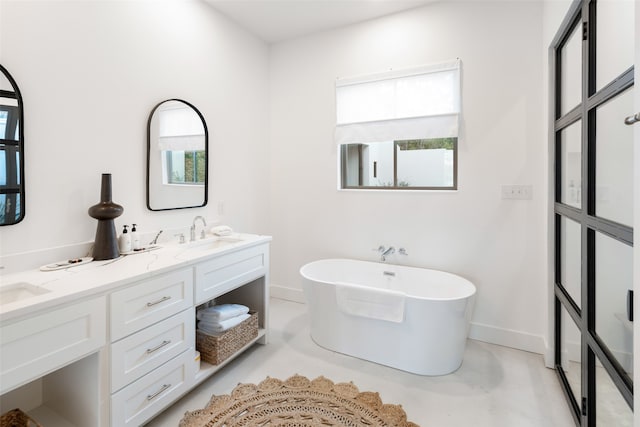 bathroom featuring a bathtub, a healthy amount of sunlight, vanity, and concrete floors