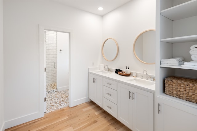 bathroom with vanity, a tile shower, and wood-type flooring