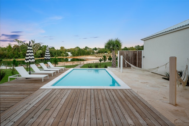 view of swimming pool featuring a deck with water view and a patio area