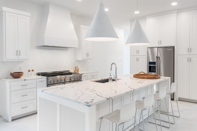 kitchen featuring appliances with stainless steel finishes, custom exhaust hood, sink, a center island with sink, and decorative light fixtures