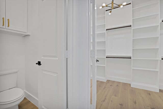 interior space featuring hardwood / wood-style flooring, toilet, and an inviting chandelier