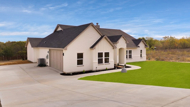 view of front of home featuring central AC, a garage, and a front lawn