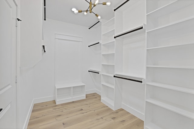 walk in closet featuring light hardwood / wood-style flooring and a chandelier