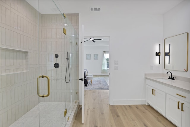 bathroom with hardwood / wood-style flooring, ceiling fan, a shower with shower door, and vanity