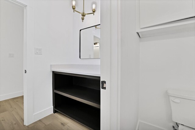 bathroom featuring hardwood / wood-style floors, vanity, an inviting chandelier, and toilet