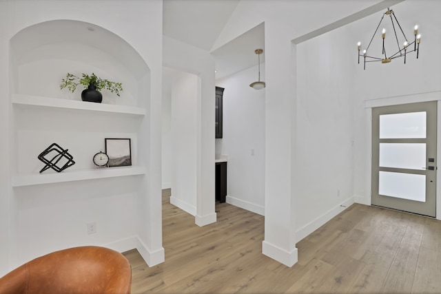 entryway with lofted ceiling, wood-type flooring, and an inviting chandelier