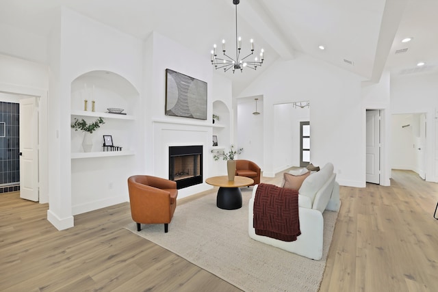 living room featuring beam ceiling, built in shelves, light hardwood / wood-style flooring, and a notable chandelier