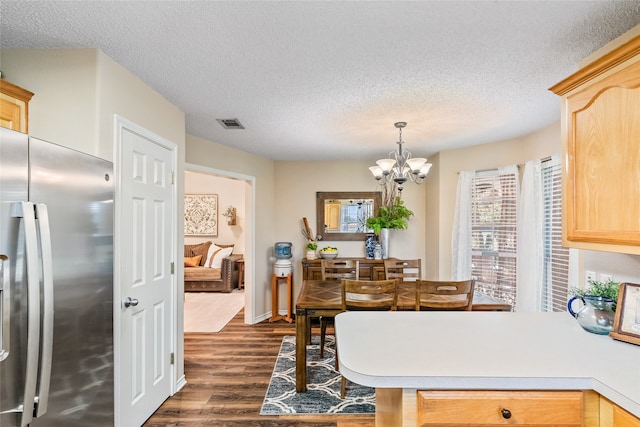 dining area with a textured ceiling, a notable chandelier, and dark wood-type flooring