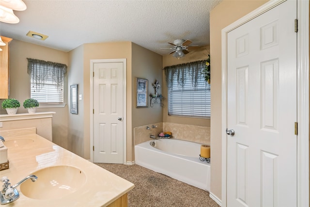 bathroom with vanity, a textured ceiling, ceiling fan, and a tub