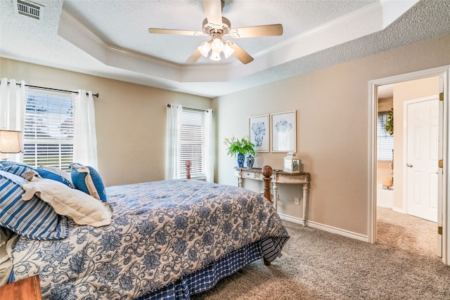 carpeted bedroom with a raised ceiling, ceiling fan, and ornamental molding