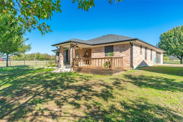 rear view of property featuring ceiling fan, a yard, and a deck