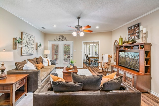 living room featuring a textured ceiling, ceiling fan with notable chandelier, light hardwood / wood-style floors, and crown molding