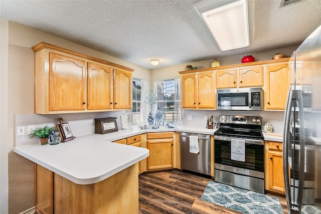 kitchen featuring a textured ceiling, dark hardwood / wood-style flooring, kitchen peninsula, and stainless steel appliances