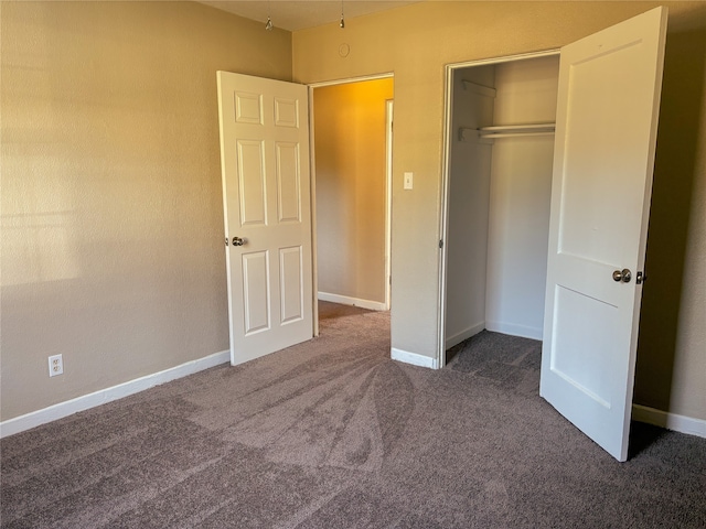 unfurnished bedroom with dark colored carpet and a closet