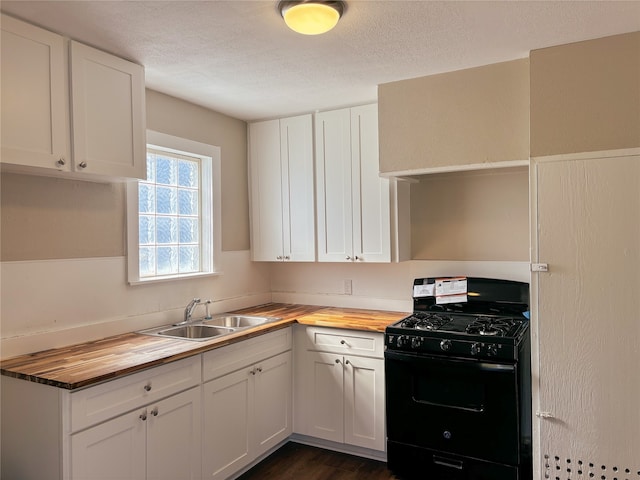 kitchen featuring butcher block countertops, white cabinets, sink, and black range with gas cooktop