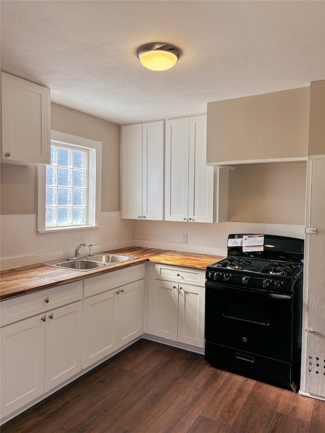 kitchen featuring wooden counters, black gas range, dark hardwood / wood-style floors, and white cabinetry