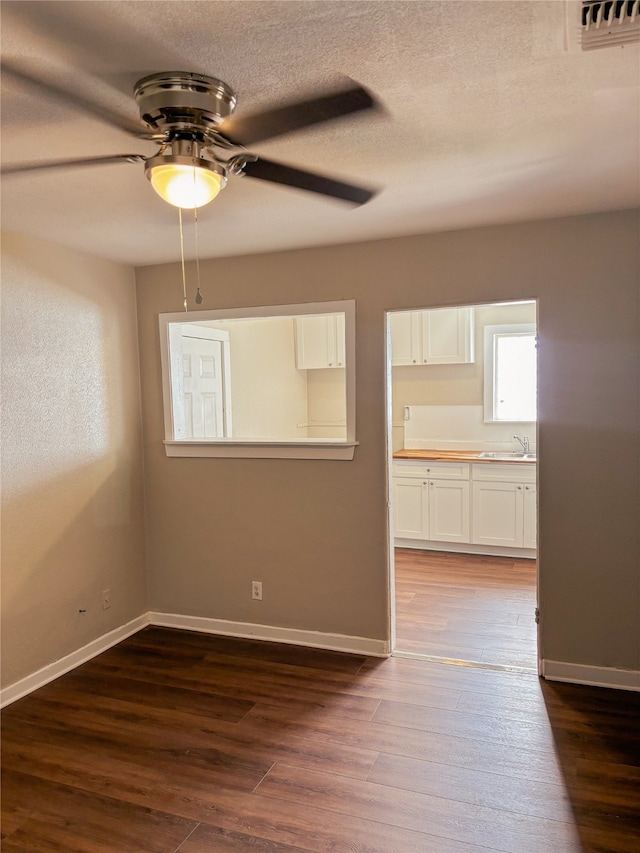 spare room with hardwood / wood-style flooring, ceiling fan, sink, and a textured ceiling