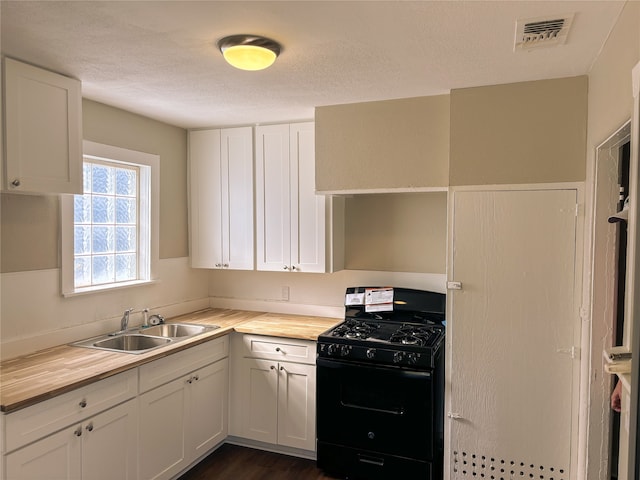 kitchen with sink, wood counters, black range with gas stovetop, a textured ceiling, and white cabinets