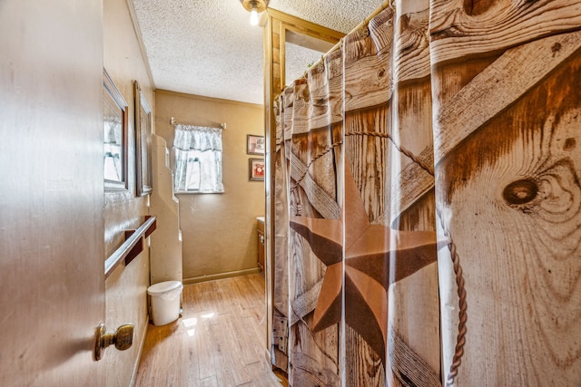 wine cellar featuring wood-type flooring, a textured ceiling, and ornamental molding