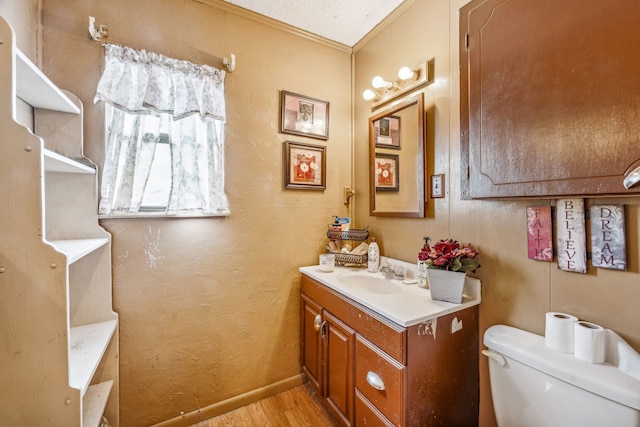 bathroom with vanity, crown molding, hardwood / wood-style flooring, toilet, and a textured ceiling