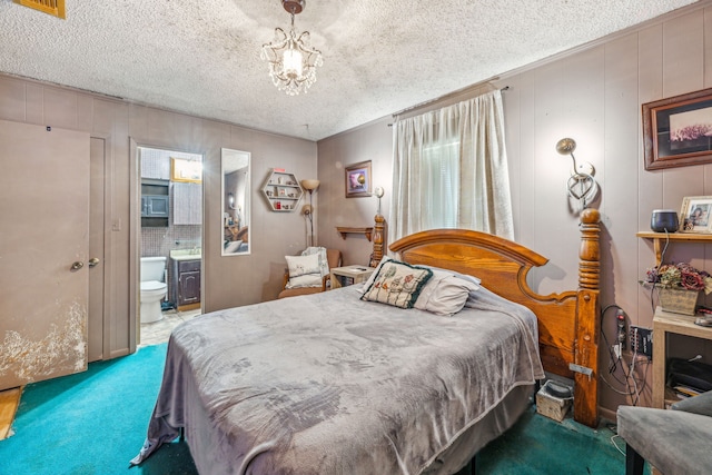 carpeted bedroom featuring ensuite bathroom, a chandelier, and a textured ceiling