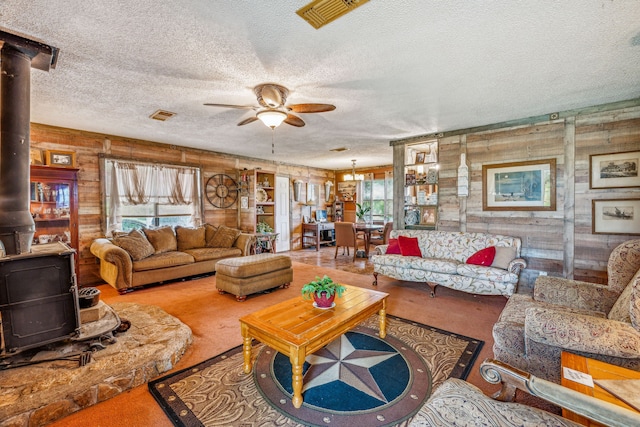 living room featuring ceiling fan, a wood stove, a textured ceiling, and a wealth of natural light