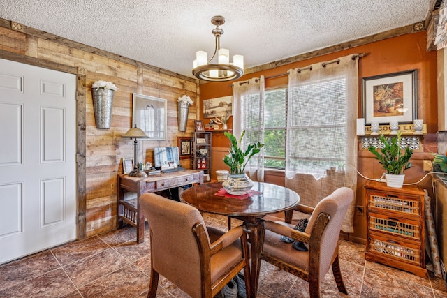 dining area featuring wooden walls, a textured ceiling, and a notable chandelier