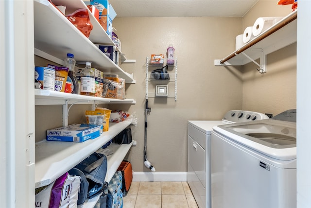 clothes washing area with washing machine and dryer and light tile patterned floors