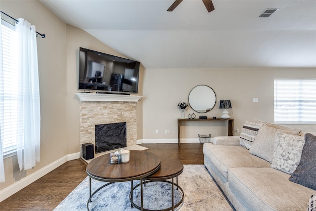 living room featuring a stone fireplace, a wealth of natural light, lofted ceiling, and hardwood / wood-style flooring