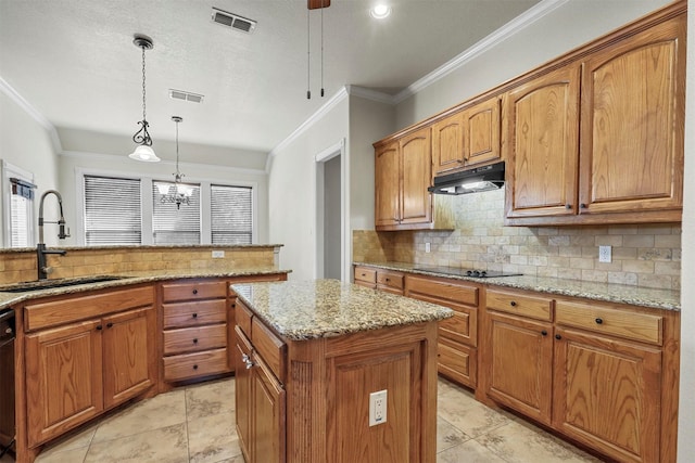 kitchen with sink, hanging light fixtures, light stone counters, black appliances, and a kitchen island