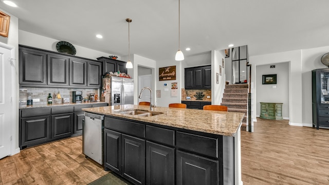 kitchen with tasteful backsplash, sink, an island with sink, and appliances with stainless steel finishes