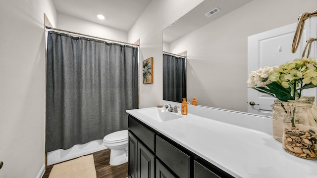 full bathroom featuring hardwood / wood-style floors, vanity, shower / tub combo, and toilet