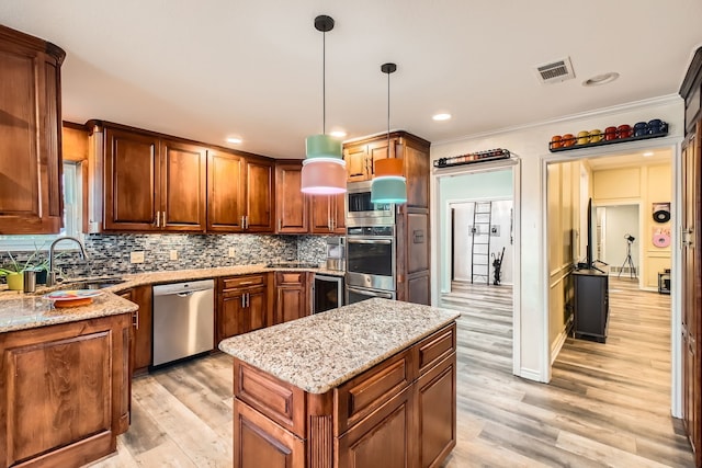 kitchen featuring appliances with stainless steel finishes, light wood-type flooring, crown molding, sink, and hanging light fixtures