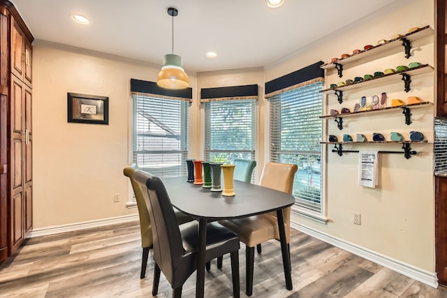 dining area with light wood-type flooring and crown molding