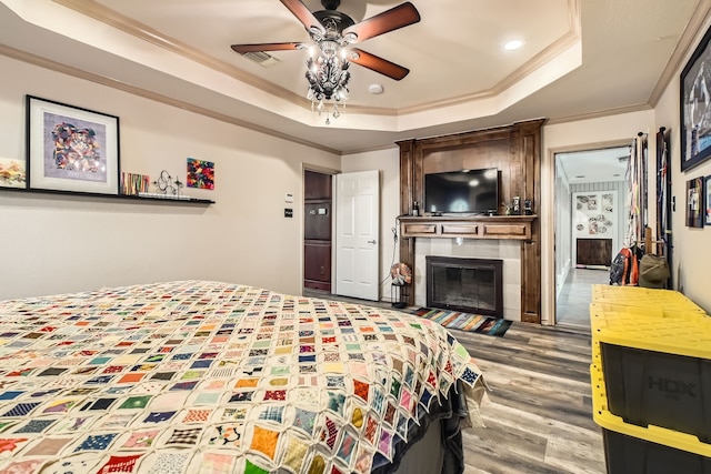 bedroom featuring a raised ceiling, crown molding, ceiling fan, and hardwood / wood-style flooring