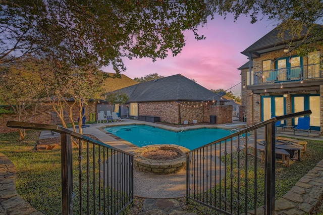 pool at dusk with a diving board and a patio area