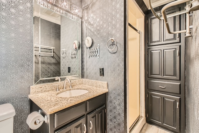 bathroom featuring wood-type flooring, vanity, toilet, and an enclosed shower